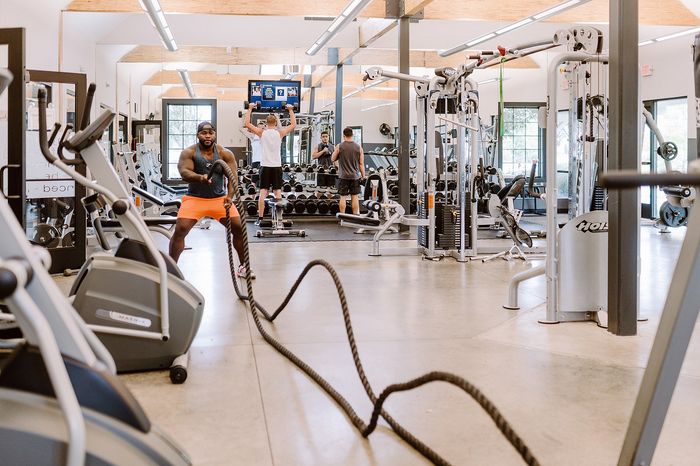 Vibrant gym interior with diverse equipment, energetic atmosphere, and people actively working out for a healthy lifestyle.