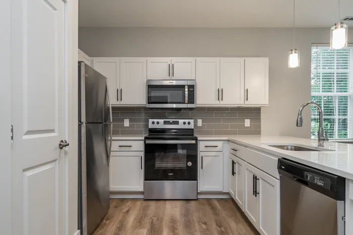 Modern kitchen design with sleek white cabinets, stainless steel appliances, and elegant lighting.