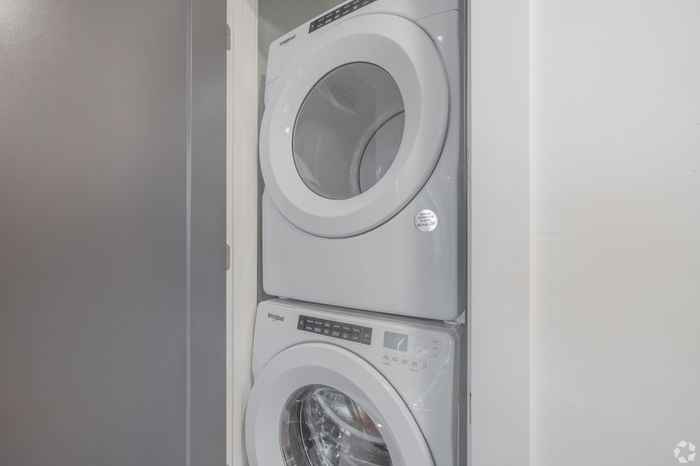 Modern stacked washer and dryer unit in a sleek laundry area, perfect for efficient apartment living.