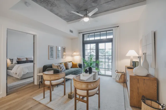 Chic and cozy living room with modern decor, featuring a plush sofa, elegant wooden chairs, and a bright window view.