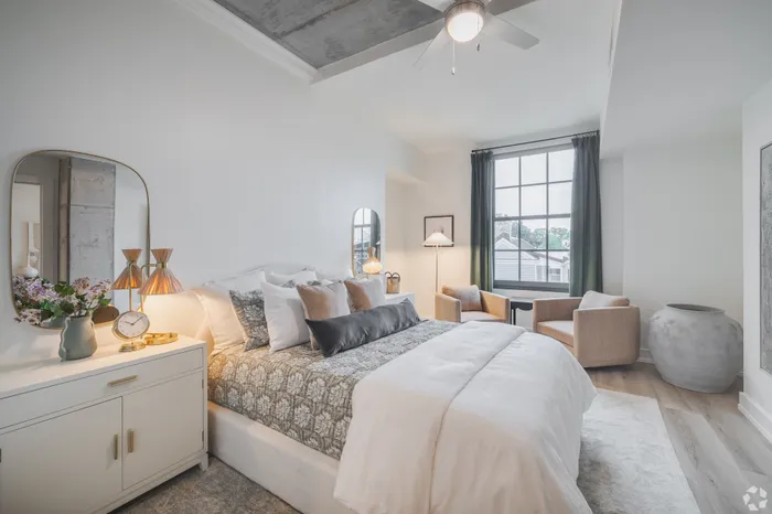 Elegant bedroom with cozy seating area, modern decor, and large window offering plenty of natural light.