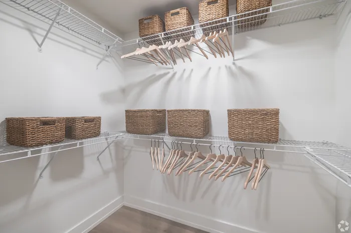 Spacious walk-in closet with organized shelving and stylish wicker baskets, perfect for elegant storage solutions.