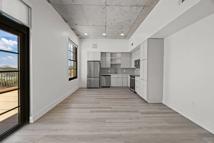 Modern open-concept kitchen with sleek appliances, large windows, and stylish flooring, offering an abundance of natural light.