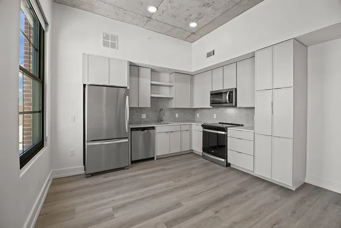 Sleek modern kitchen with stainless steel appliances, elegant cabinetry, and natural light streaming through a large window.