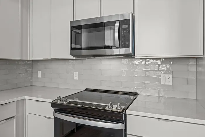 Modern kitchen with sleek stainless steel appliances, glossy subway tile backsplash, and pristine white cabinetry for a contemporary look.