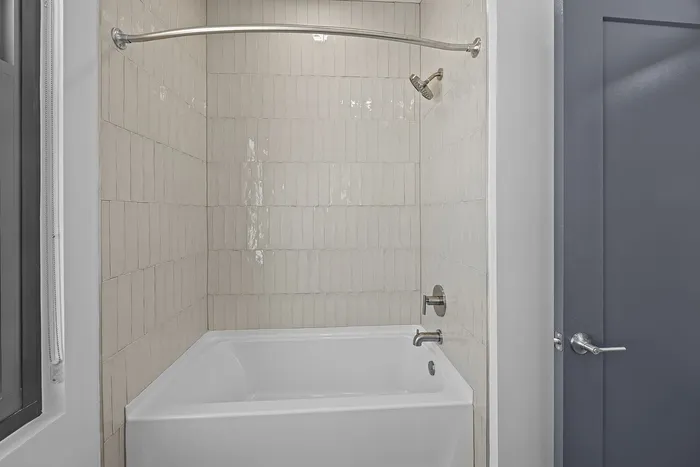 Elegant bathroom featuring a modern white bathtub and chic tiled walls, perfect for relaxation.
