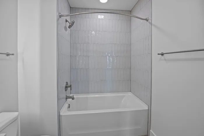 Elegant bathroom showcasing sleek white tiles, a modern bathtub, and contemporary fixtures, creating a serene spa-like ambiance.