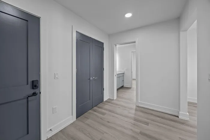 Modern apartment entryway featuring sleek gray doors, elegant laminate flooring, and a glimpse of the bright, spacious interior.