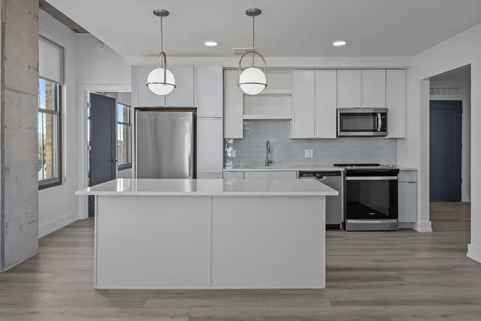 Modern kitchen with sleek white cabinetry, stainless steel appliances, and elegant pendant lighting.