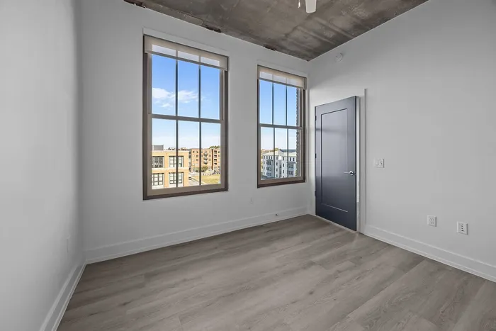Bright and airy apartment room with large windows offering stunning views of the cityscape and elegant wood flooring.