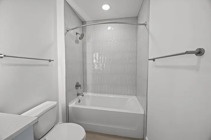 Elegant bathroom featuring a modern shower-tub combination with sleek tile backsplash and recessed lighting for a luxurious experience.