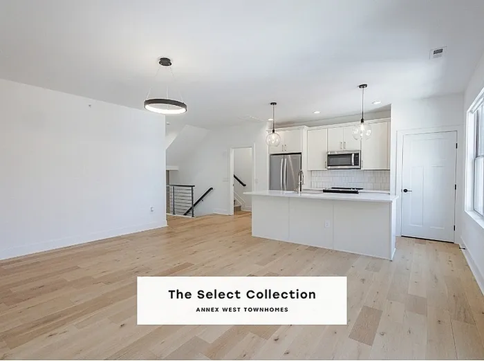 Bright and modern kitchen-living space in The Select Collection at Annex West Townhomes with sleek white cabinetry and stylish pendant lighting.