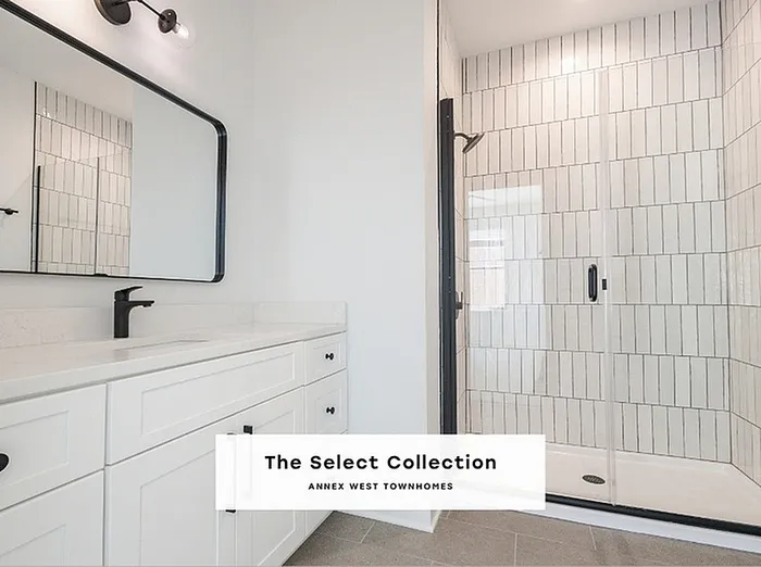 Modern bathroom featuring a sleek glass shower, elegant white vanity, and stylish lighting in The Select Collection at Annex West Townhomes.