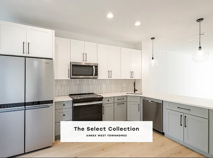 Modern kitchen in The Select Collection at Annex West Townhomes featuring sleek cabinetry, stainless steel appliances, and elegant pendant lighting.