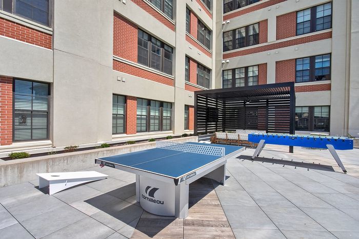 Vibrant outdoor leisure area featuring a ping pong table, foosball, and modern seating under a stylish pergola.