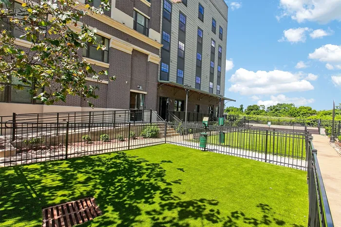 Charming apartment building with modern architecture, complemented by lush green landscaping and a sunny outdoor space.