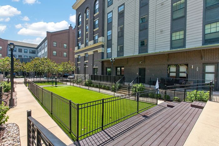 Charming apartment exterior with modern architecture, lush green lawn, and inviting pathways in a vibrant community setting.