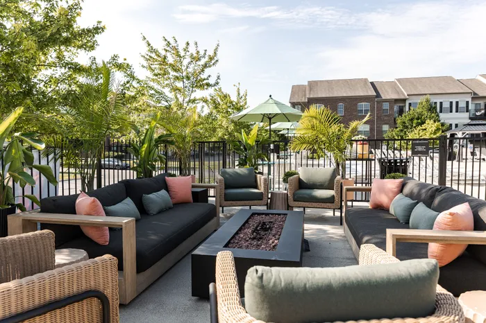 Chic outdoor patio setup with stylish lounge furniture, vibrant cushions, and lush greenery, perfect for relaxing and entertaining.