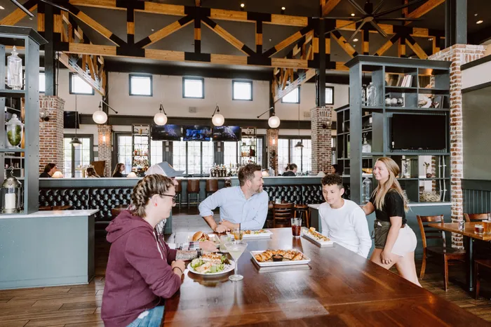 Chic dining space with rustic wood accents, featuring a lively group enjoying gourmet meals under stylish pendant lights.