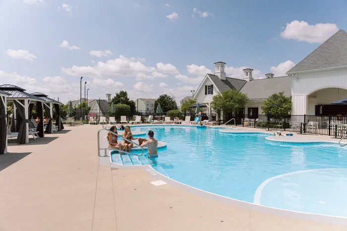 Inviting outdoor pool area at a modern apartment complex, featuring stylish cabanas and sun loungers for relaxation.