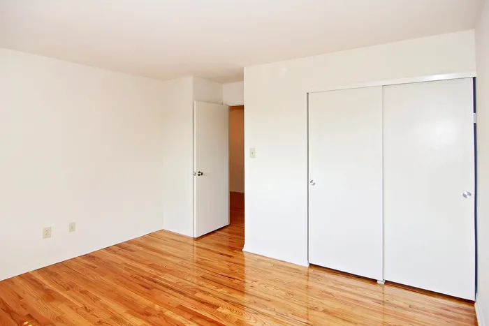 Bedroom with hardwood floors and closet along the wall