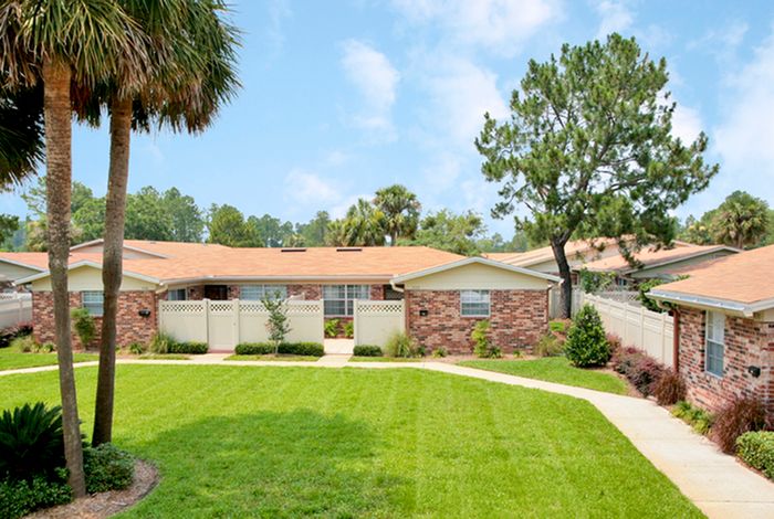 Beach Villas Apartments, exterior, palm trees, large grassy area, walk ways, single story brick buildings, privacy fences,