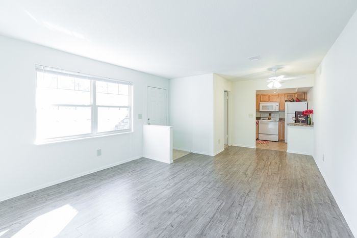 Beach Villas Apartments, interior, living room, dining room, kitchen, open flow, large window, wood floor, wood cabinets, white refrigerator, white stove/oven, microwave, front door