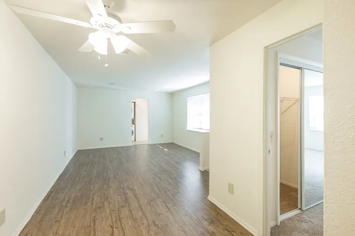 Beach Villas Apartments, interior, spacious living room, wood floors, ceiling fan, doorway to bedroom, mirrored closet door