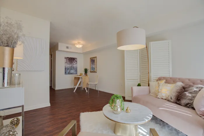 Canyon Square Apartments & Townhomes, interior, living room, wood floor, furry white area rug, pink sofa and chair, lamps, dining area, table for two