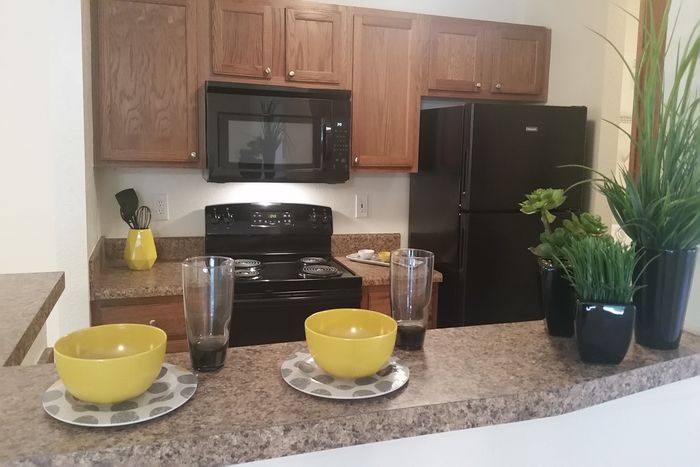 Creekside Park Apartments, interior, kitchen, pass through opening, wood cabinets, black appliances, microwave, stove/oven, refrigerator,