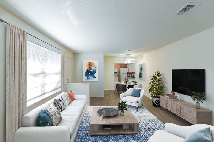 Beach Villas Apartments, interior, living room, dining room, kitchen, open flow, large window, white couch, blue and white area rug, wood floor, tv, arm chairs, dining table, wood cabinets, white refrigerator