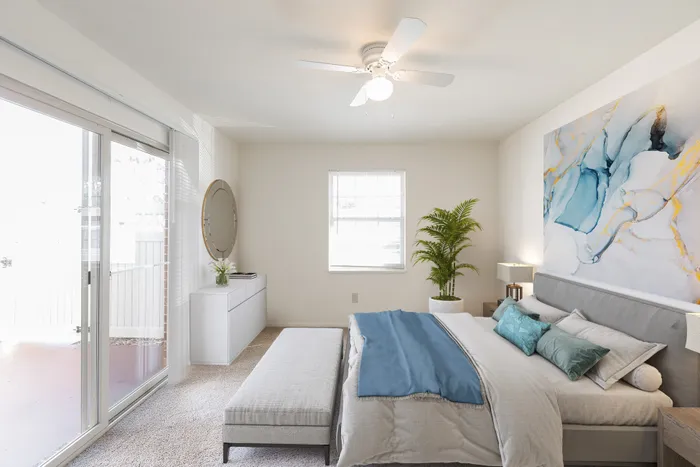 Beach Villas Apartments, interior, bedroom, blue and gray decor, large sliding glass doors, window, ceiling fan, dresser with mirror, wall decor, carpet