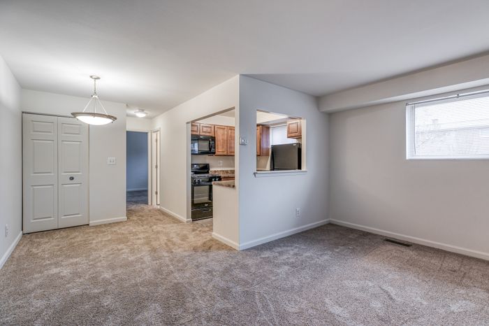 Crain Court Apts, Interior, Living room, dining room, kitchen, plush wal to wall carpet, chandiler, window in living room and kitchen, wall kitchen from living room to kitchen