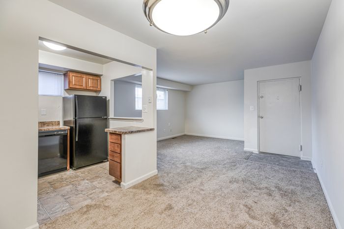 Crain Court Apts, Interior, Living room, dining room, kitchen, plush wal to wall carpet, chandiler, window in living room and kitchen, wall kitchen from living room to kitchen, front door with tile mud area