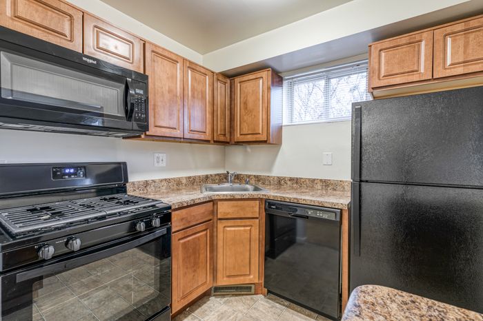 Crain Court Apts, Interior, Kitchen, Breakfast bar, honey color cabinets, window in kitchen, mrble like counter tops, Black appliances, Fridge, gas range,microwave, dishwasher, GFI outlet
