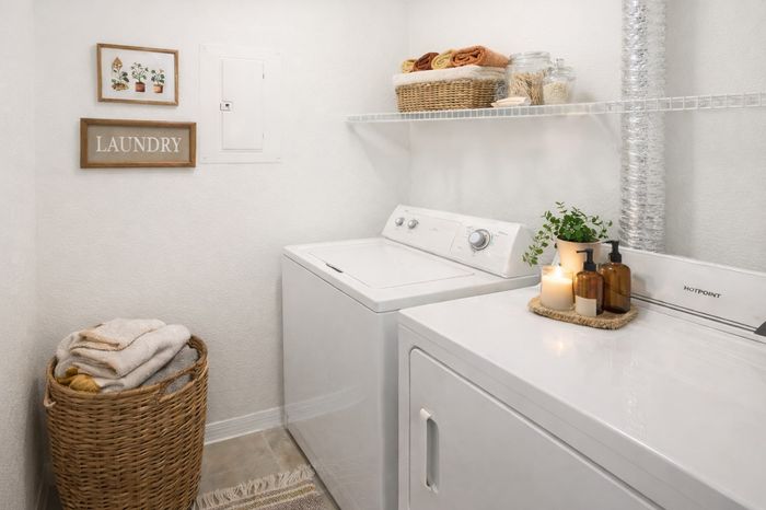 Laundry Room. Tray with plant, amber bottles, and candle. Laundry hamper. Folded towels.