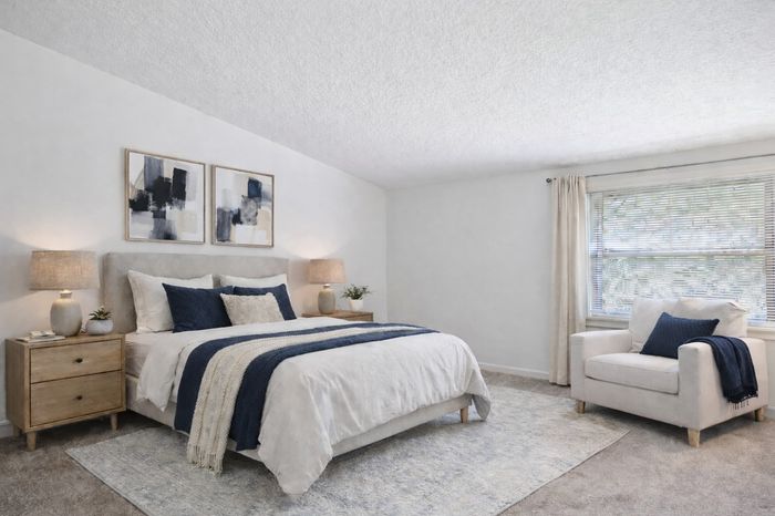 Bedroom with cathedral ceiling. navy accents, bed, nightstand, arm chair