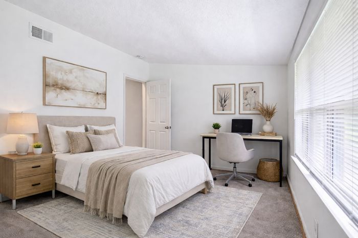 Bedroom with beige accents, plants, night stand, desk