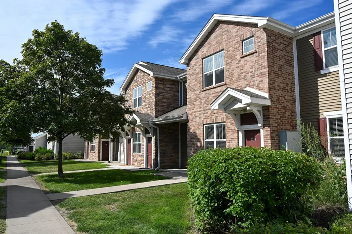 Charming townhouse with brick exterior and lush greenery, offering a cozy and inviting atmosphere.