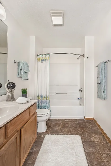 Bright and modern bathroom featuring elegant tile flooring, a sleek vanity, and a stylish shower area with vibrant floral curtain.