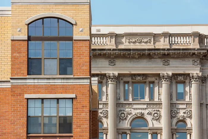 Stunning architectural contrast showcasing elegant brickwork next to intricate classical stone facade with detailed columns.