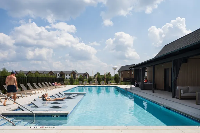 Inviting outdoor pool area with stylish loungers and relaxing cabanas under a clear blue sky, perfect for leisure and sunbathing.