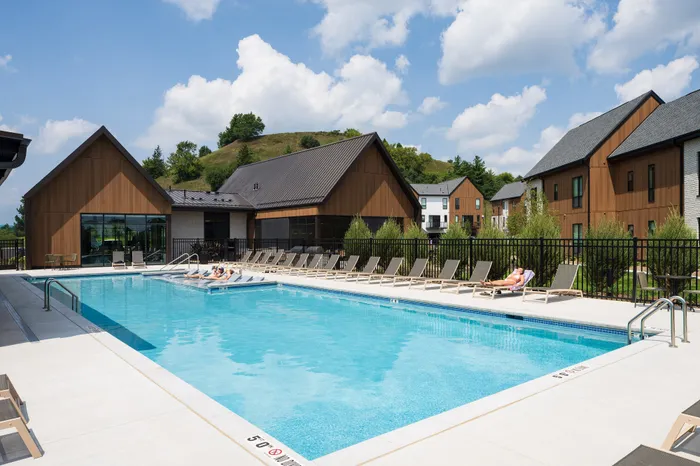 Inviting outdoor pool area with modern lounge chairs and scenic hillside views, perfect for relaxation.