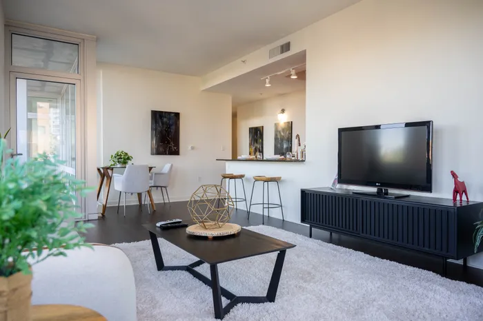 Modern living space with a sleek TV setup, a stylish coffee table, open kitchen, and a cozy dining area that invites relaxation and entertaining.