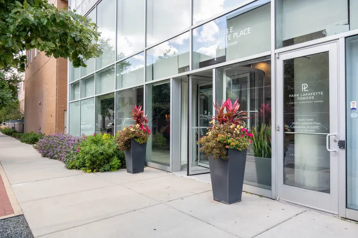 Modern glass entrance to Park Lafayette Towers with beautiful flower arrangements and upscale design.