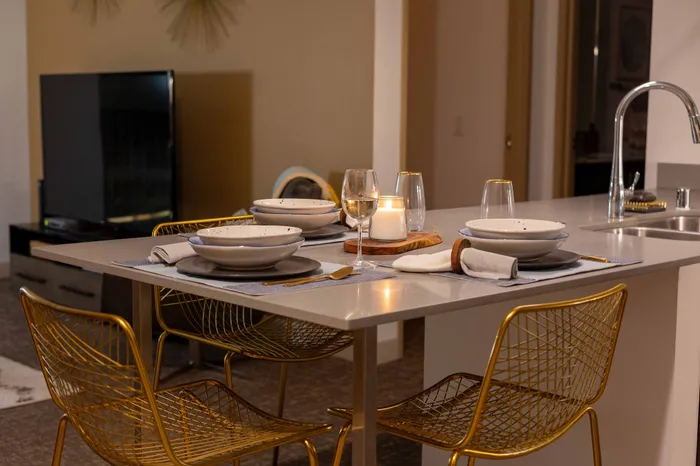 Elegant dining area featuring modern gold wire chairs, a sleek countertop, and ambient candlelight for a cozy atmosphere.