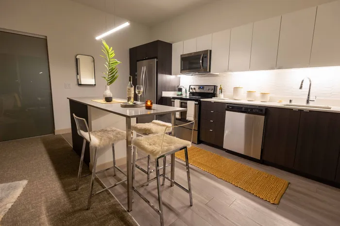 Modern kitchen with sleek cabinetry, stainless steel appliances, and cozy island seating in an inviting open-plan layout.