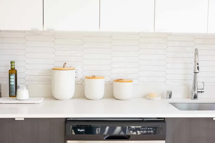 Modern kitchen with sleek white cabinetry, stainless steel faucet, and stylish hexagonal tile backsplash.