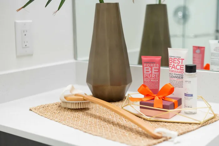 Chic bathroom vanity displaying premium skincare products, a stylish brown vase, and a luxurious body brush on a modern countertop.