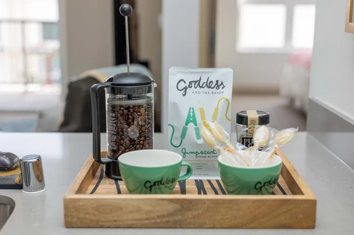 Inviting kitchen setup featuring a French press, gourmet coffee beans, and stylish mugs on a wooden tray.